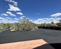 a driveway with cracks in it and a fence in the background